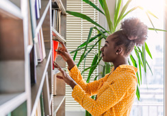 Woman pulling a book from a bookshelf